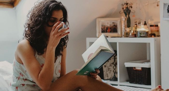 woman drinking tea relaxing and reading in bed feature 700x375 1.jpg.optimal