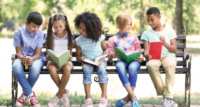 image of kids reading books on a park bench.jpg.optimal