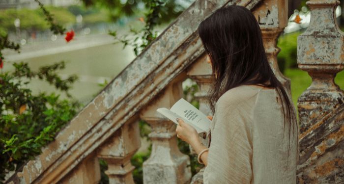 a fair skinned woman reading on antique steps.jpg.optimal