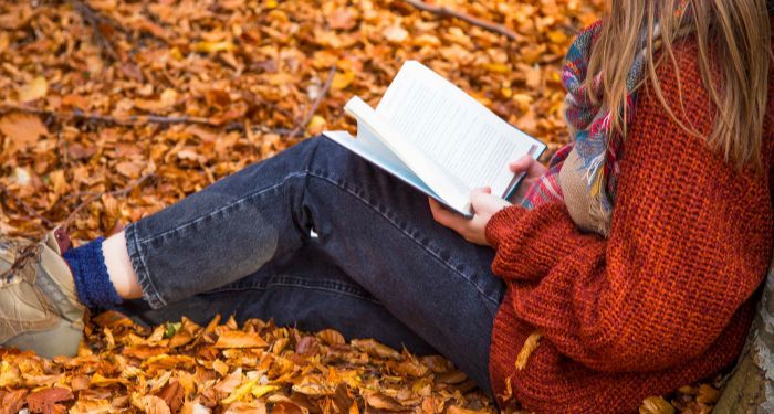 kid reading in pile of leaves in fall autumn.jpg.optimal