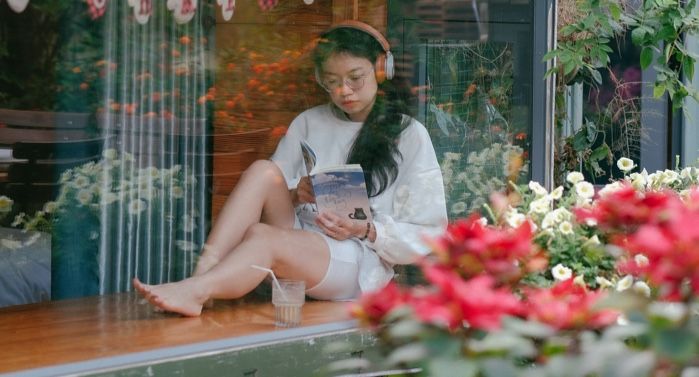 Asian woman reading near storefront windo.jpg.optimal