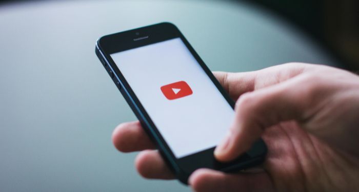 hand holding phone with youtube loading screen on face.jpg.optimal